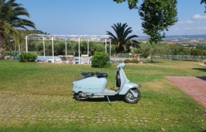 residence per le vacanze con piscina e prato con una lambretta parcheggiata